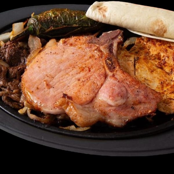 Los Compas Independence's sizzling platter with pork chop, steak, chicken, grilled pepper, and tortilla.
