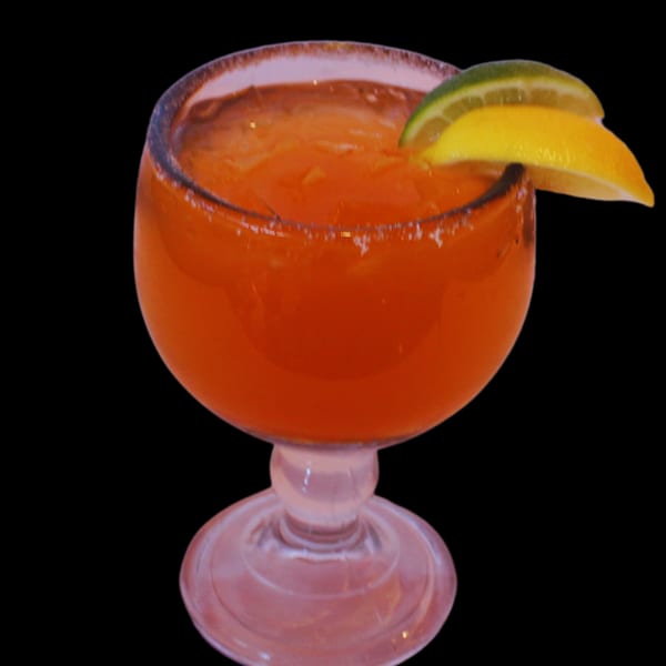 A vibrant orange margarita with a salted rim, garnished with a lime and lemon slice.